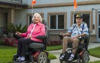 two seniors in electric wheelchairs outside