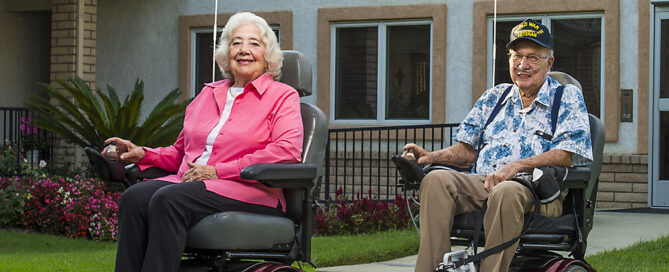 two seniors in electric wheelchairs outside