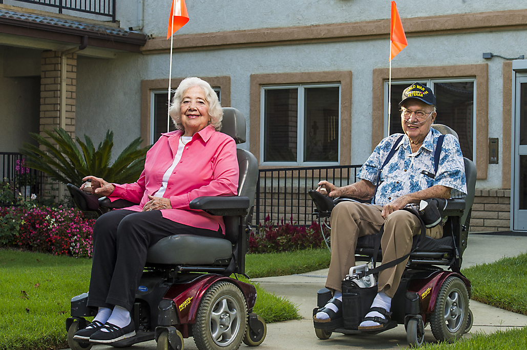 two seniors in electric wheelchairs outside