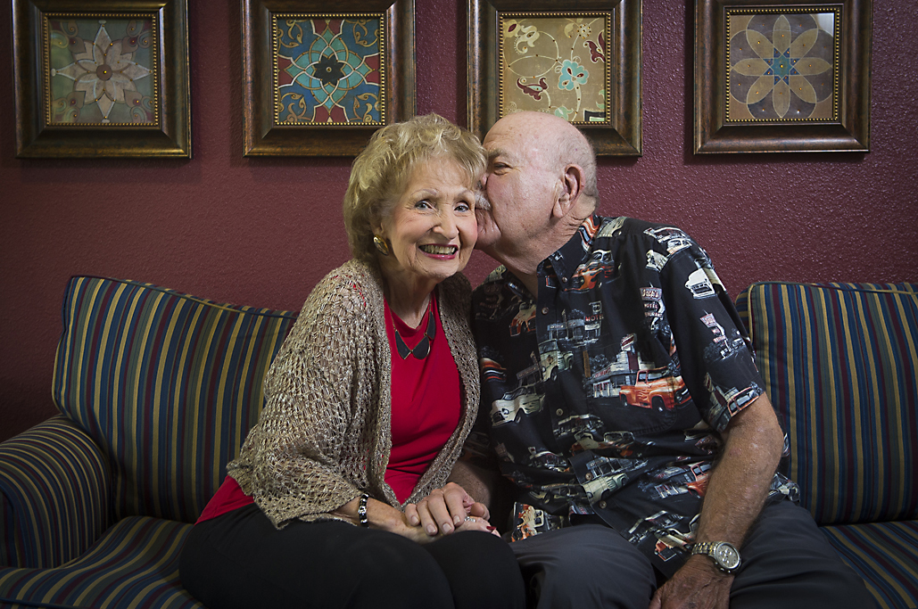 senior male kissing senior female's cheek on the sofa