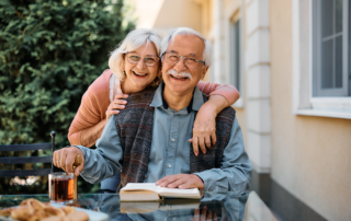 An elderly couple smiling for a group photo outside