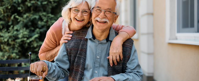 An elderly couple smiling for a group photo outside