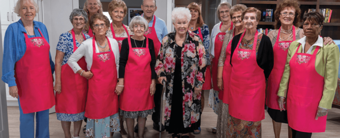 group photo of senior women in pink aprons