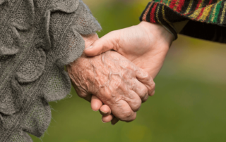 elderly mother and adult child holding hands