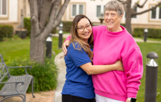 young female staff member hugging senior female resident