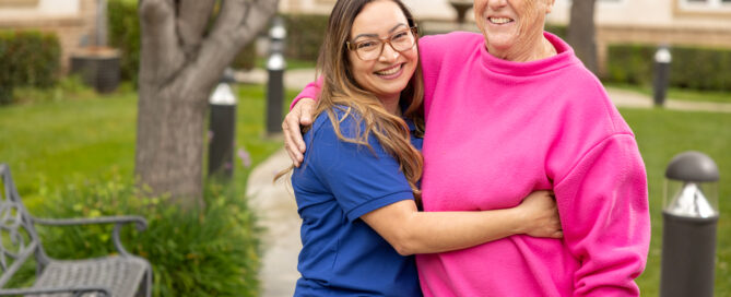 young female staff member hugging senior female resident