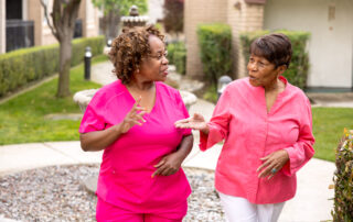 female nurse and female senior resident walking and talking outdoors