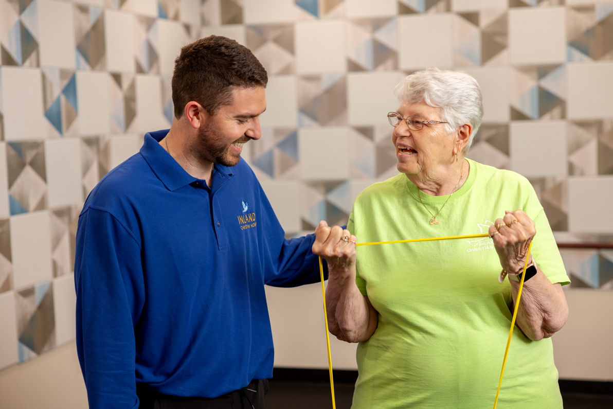 male physical therapist assisting senior female resident working out