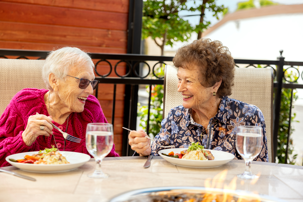 two female senior residents enjoying a meal outdoors