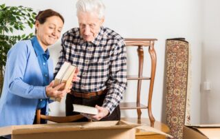 woman helping senior man pack books into a moving box