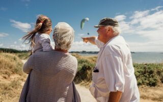 Grandparents walking their small grand daughter on a beach